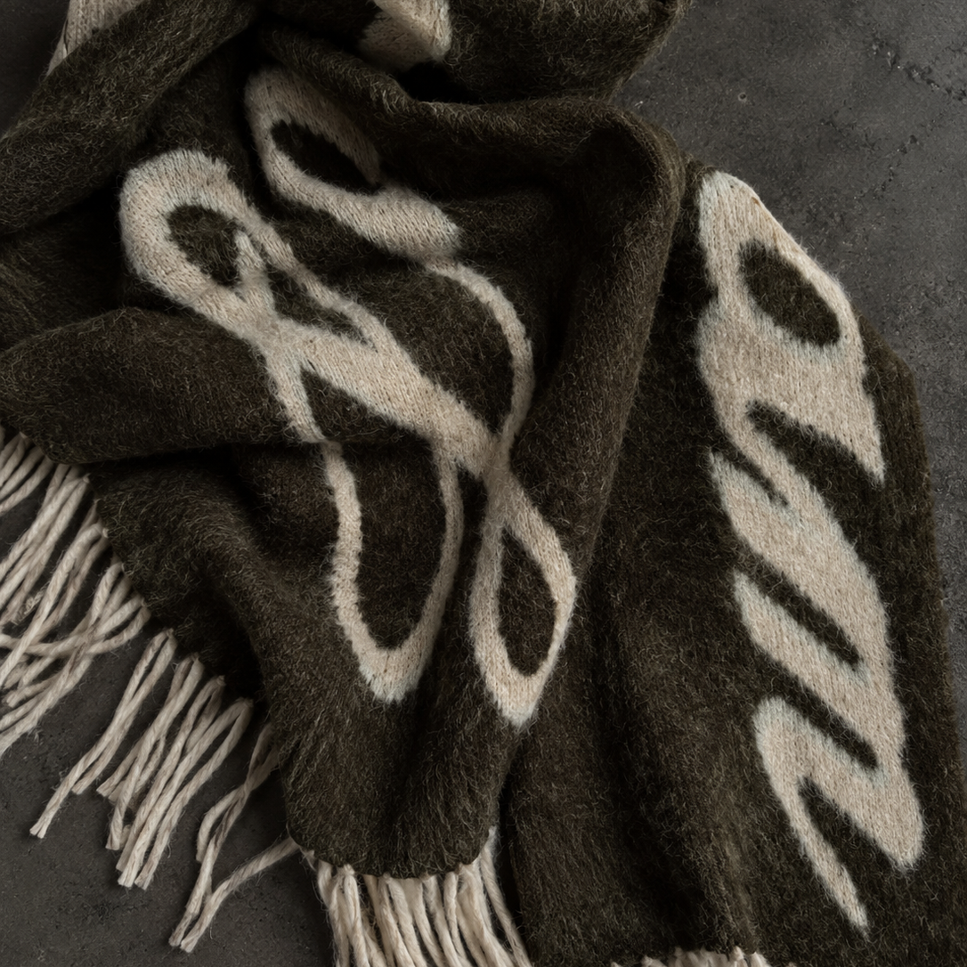 dark grey scarf with LAAGAM logo and white fringes on a black concrete background
